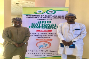Zwei Männer vor einem Banner mit der Aufschrift "3. Nationalkonferenz" mit einer Säule und Deckenbeleuchtung im Hintergrund.