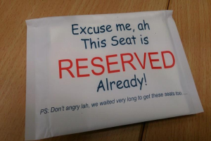 Ein hölzerner Tisch mit einem Papier, auf dem steht: "Entschuldigung, dieser Sitz ist bereits reserviert."