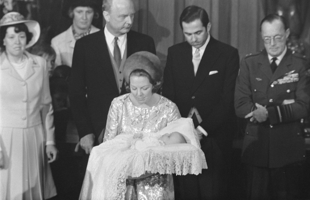 Königin Elizabeth II. hält ihren neugeborenen Sohn, Prinz Philip, während Prinz Philip, Herzog von Edinburgh, neben ihr in einem Anzug und einer Krawatte steht, mit Vorhängen im Hintergrund.