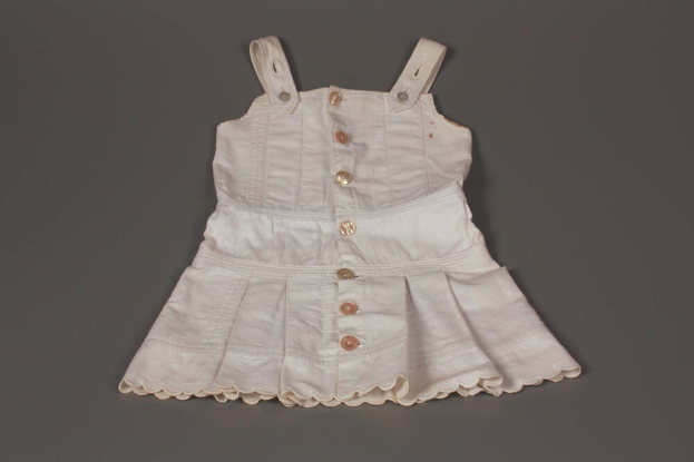 Weißes Kleid mit rundem Ausschnitt, kurzen Ärmeln und vollem Rock mit symmetrisch angeordneten Knöpfen auf einem grauen Hintergrund, Stoff mit feiner Schimmer.