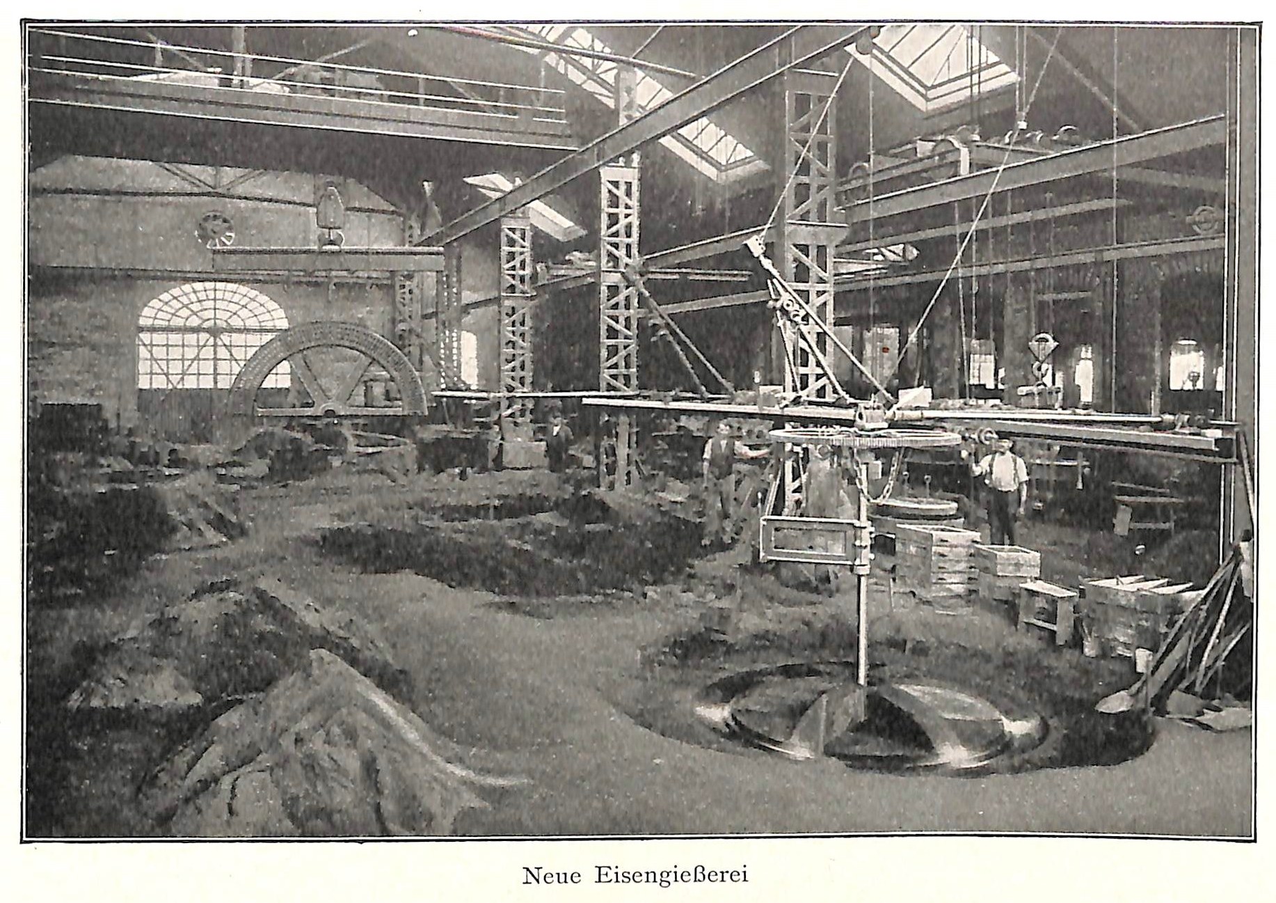 Schwarz-weiß-Foto einer Fabrik mit Arbeitern, die an einer Maschine arbeiten, umgeben von Metallstangen und -pfählen, beschriftet mit 'Neue Eisenglebeerei, die erste Fabrik in Deutschland' unten.