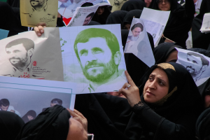 Eine Gruppe iranischer Frauen in schwarzer Kleidung, einige mit Brille, hält Fotos von Präsident Mahmoud Ahmadinejad während einer Kundgebung in Tehran hoch.