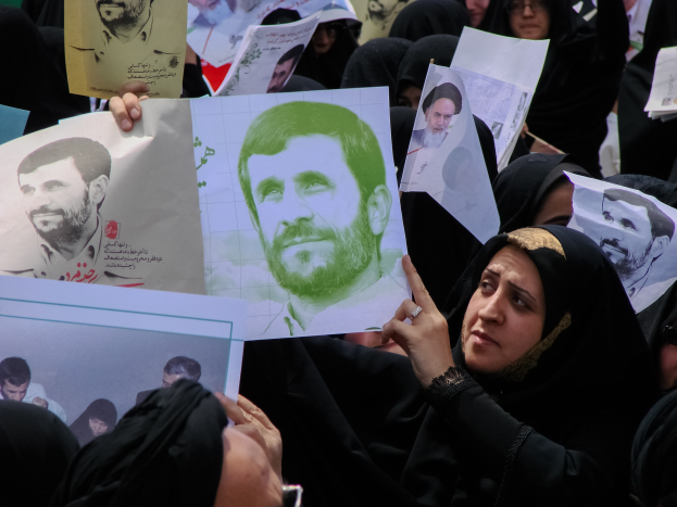 Eine Gruppe iranischer Frauen in schwarzer Kleidung, einige mit Brille, hält Fotos von Präsident Mahmoud Ahmadinejad während einer Kundgebung in Tehran hoch.