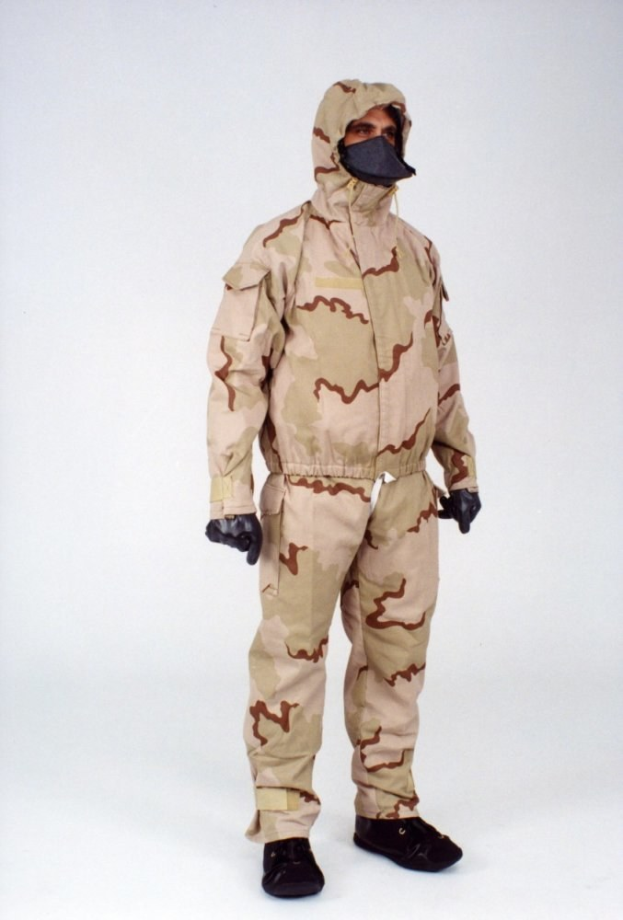 Eine Person in einem camouflagegemusterten Schutzoverall und Kapuze steht vor einem weißen Hintergrund.