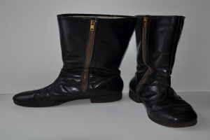 Schwarze Lederstiefel mit silbernen Reißverschlüssen auf einer weißen Oberfläche, mit einem eleganten und glänzenden Finish.
