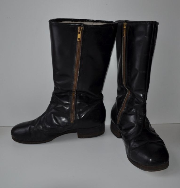 Schwarze Lederstiefel mit silbernen Reißverschlüssen auf einer weißen Oberfläche, mit einem eleganten und glänzenden Finish.