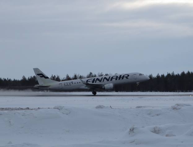 Finnair Airbus A320-200 auf einer verschneiten Landebahn am Helsinki Airport mit Bäumen und einem klaren blauen Himmel im Hintergrund.