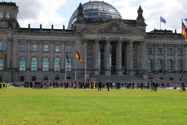 Gruppe von Menschen, die vor dem Reichstaggebäude in Berlin, Deutschland, Fahrräder fahren.