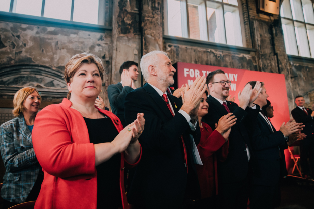 Gruppe von Menschen, die vor einer Menge jubeln, mit einem Wahlsiegbanner im Hintergrund.