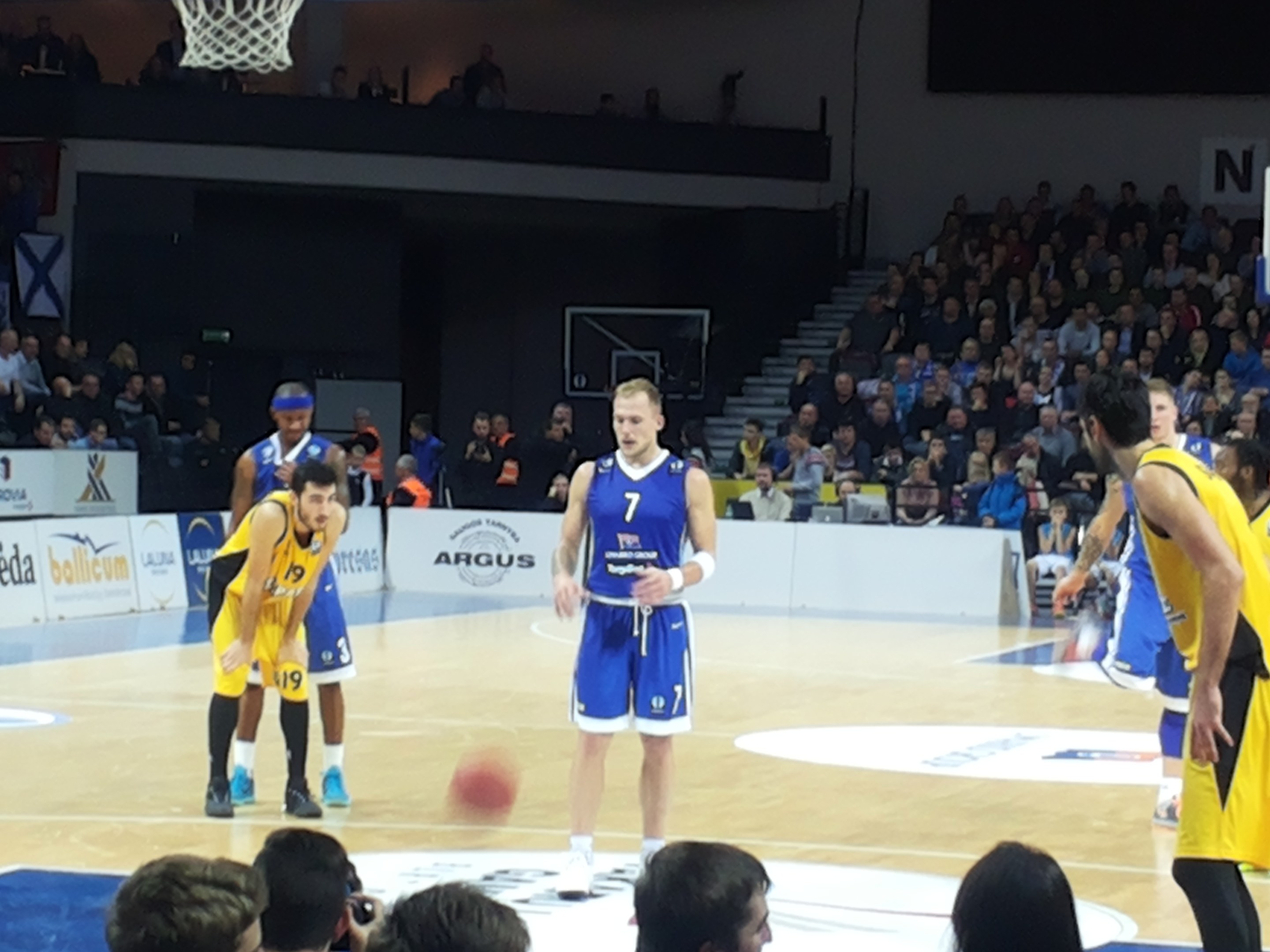 Eine Gruppe von Männern in blauen und gelben Uniformen spielt Basketball auf einem Court mit Zuschauern in den Rängen während eines Spiels zwischen Fenerbahçe und Real Madrid in der 7days Eurocup Regular Season Round 2.