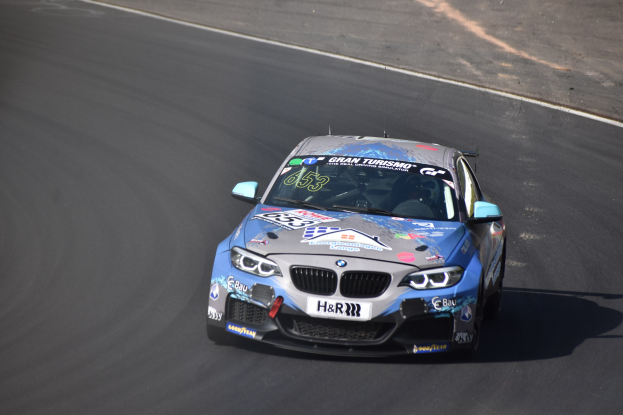 BMW M2 GT3 Rennauto auf der Rennstrecke mit Text und Zahlen auf der Karosserie.