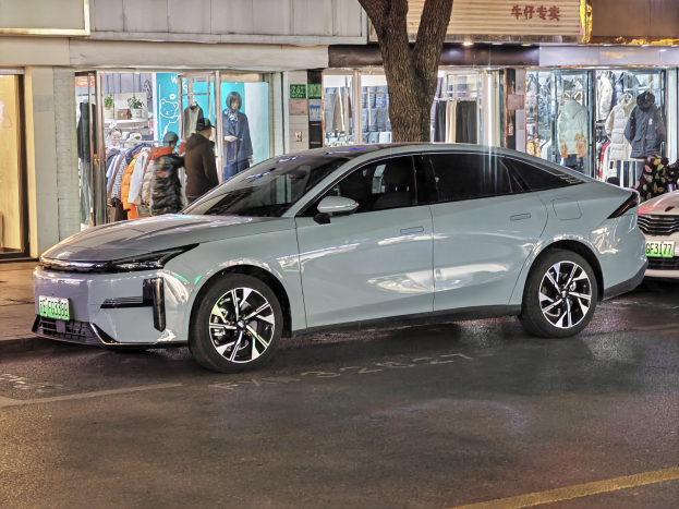 Ein Mitsubishi Lancer EV auf einer nächtlichen Stadtstraße geparkt, umgeben von beleuchteten Schaufenstern und Schaufensterpuppen.