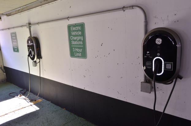 Eine Ladestation für Elektrofahrzeuge in einer Tiefgarage mit zwei Ladesäulen an der Wand und Informationsschildern, die den Boden zeigen.