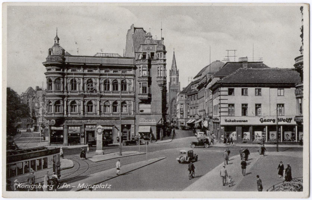 Schwarz-weißes Foto einer belebten Münchner Stadtstraße mit Fußgängern, Fahrzeugen und Fenstern an den Gebäuden, Bäumen im Hintergrund und Text unten.