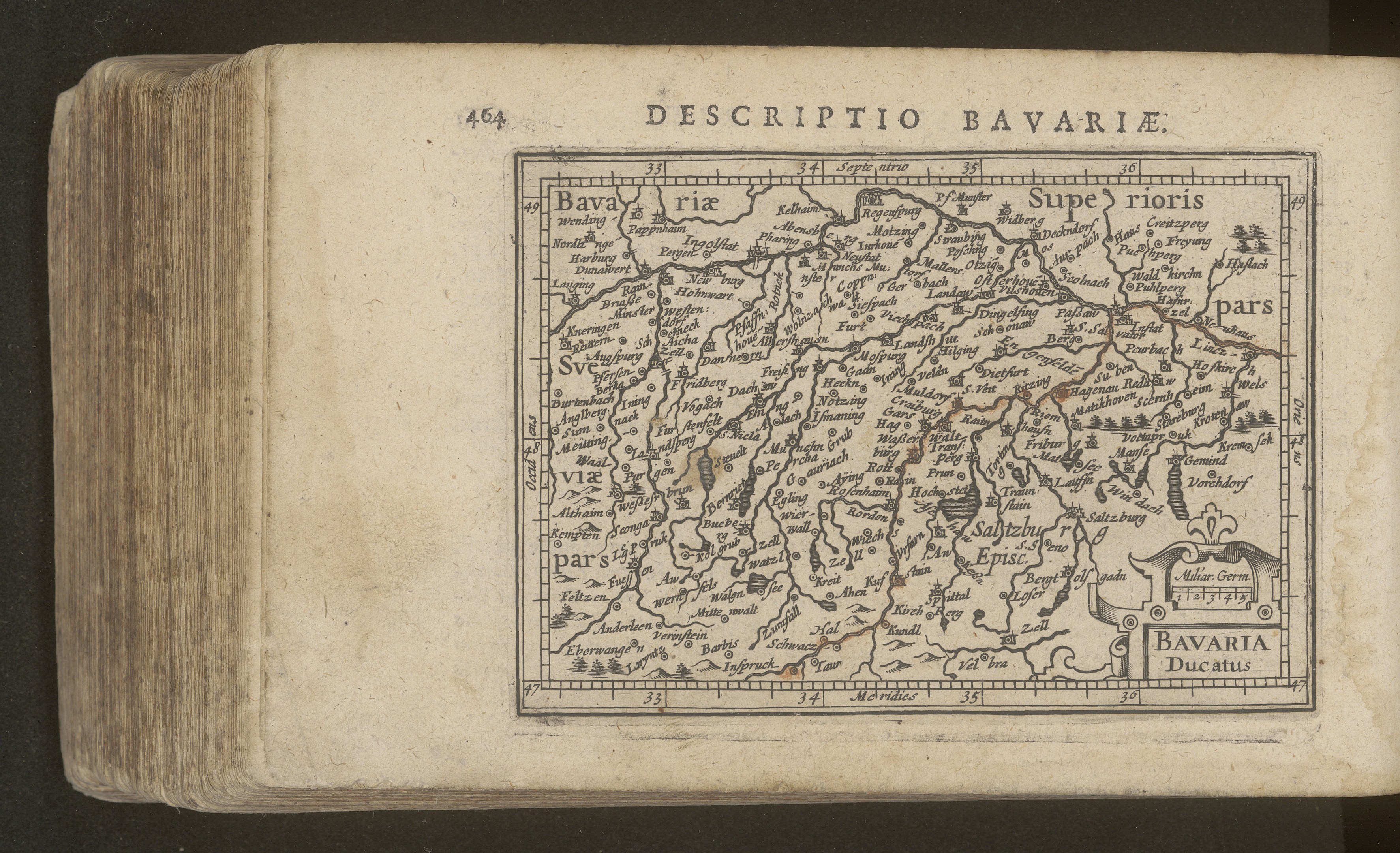 Altes Buch mit detaillierter Karte von Bayern vor schwarzem Hintergrund, die geographische Merkmale zeigt.