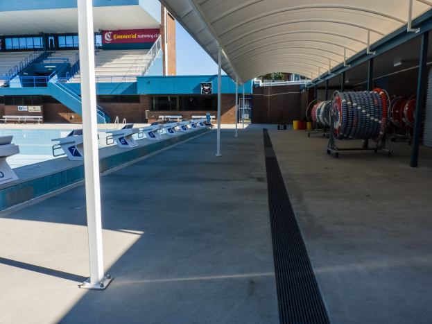 Großer Hallenbad mit leeren Stuhlreihen, einem Gebäude, Treppen, Geländern und Informationsschildern im Hintergrund an der University of Texas at Austin.